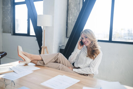 A blone businesswoman in her office talking on the phone
