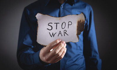Man showing Stop War text on burned paper.