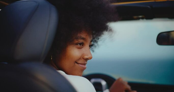 Portrait of beautiful young black african american woman smiling in her car on epic road trip, travel and adventure nomadic lifestyle