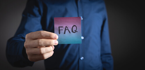 Man showing FAQ on sticky note.