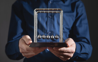Male hand showing Newton's cradle balls . Business