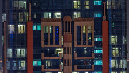 Fototapeta na wymiar Night aerial view of apartment building glass window facade with illuminated lighted workspace rooms timelapse.