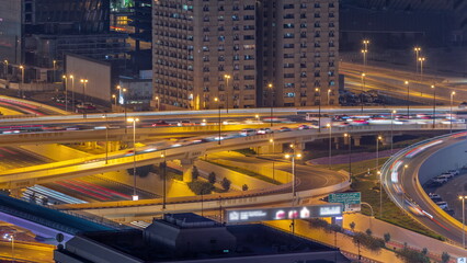 Fototapeta na wymiar Big highway junction and Dubai water canal with pedestrian bridge over it aerial night timelapse.