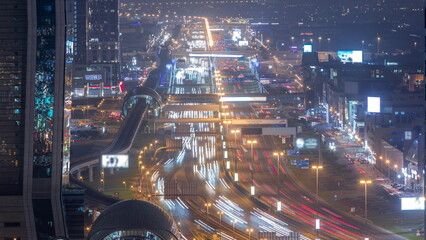 Fototapeta na wymiar Busy Sheikh Zayed Road aerial night timelapse, metro railway and modern skyscrapers around in luxury Dubai city.