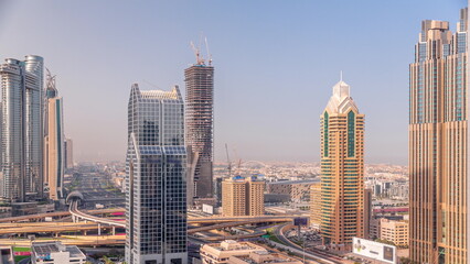 Fototapeta na wymiar Dubai city skyline panoramic view with metro and cars moving on city's busiest highway aerial timelapse