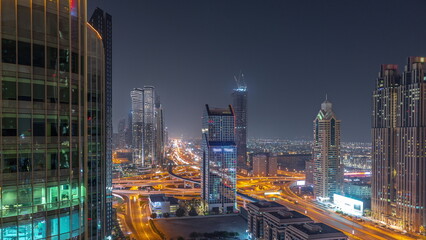Fototapeta na wymiar Dubai city skyline panoramic view with metro and cars moving on city's busiest highway aerial night timelapse