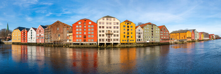 Obraz premium Wide panoramic view of old colorful wooden houses along river Nidelva in the Brygge district in Trondheim, Norway