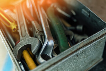 Fototapeta premium Metal box with set of wrenches and screwdrivers close-up. Working tool of locksmith or mechanic. Sunlight glare. Background.