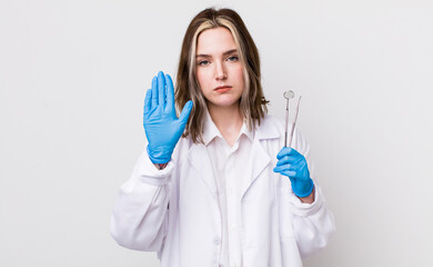 pretty caucasian woman looking serious showing open palm making stop gesture. dentist concept