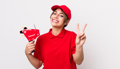 pretty hispanic woman smiling and looking friendly, showing number two. packer concept