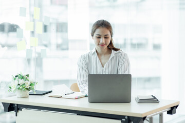 Cropped image of professional Asian businesswoman working at her office via laptop, young female manager using portable computer device while sitting at modern loft, flare light, work process concept