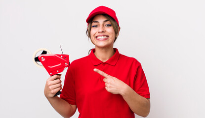pretty hispanic woman smiling cheerfully, feeling happy and pointing to the side. packer concept