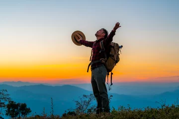 Tuinposter Men hike for tusks, happy to travel on the top of the mountain, sunset with a large backpack, lifestyle travel, adventure travel in the summer, outdoor travel alone in the forest. © EKKAPON