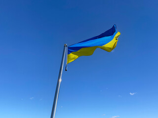 Ukrainian flag on flagstaff against blue sky