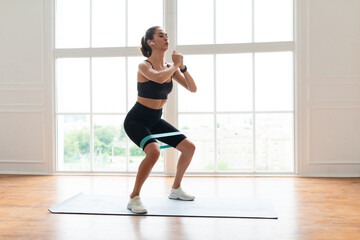 Fototapeta premium Woman In Black Sportswear Exercising With Elastic Band