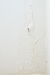 The white paint wall is peeling and a long crack in the bedroom.