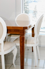 Brown polished dining table and white chairs. Vertical photography.