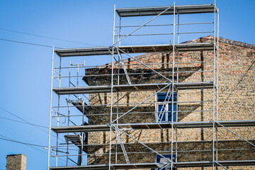 Reconstruction of an old brick house. Scaffolding for construction, construction site. Selective focus