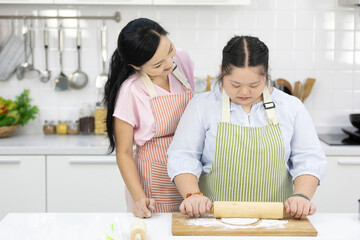 mother support young teenage girl or her daughter rolling out dough and flour on kitchen table