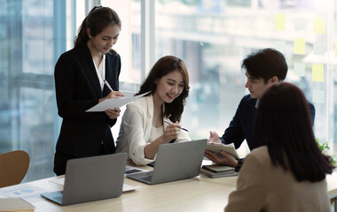 Young beautiful woman gesturing and discussing something with smile while her coworkers listening to her sitting at the office table