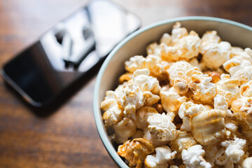 Popcorns bowl beside a smartphone with earphones. Break. Movie time
