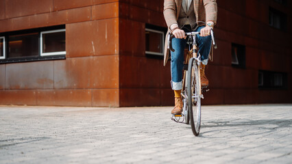 Midsection Close up leg shot of a businessman with bicycle commuting to the office. Modern building. Copyspace