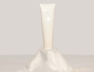 Cream mock-up on a white silk fabric podium. Gentle skin care concept.