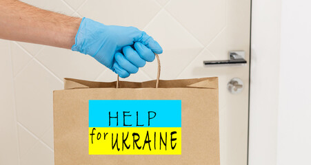 A man holds a box of aid for Ukrainian refugees and poor citizens who find themselves in a war between Ukraine and Russia. Humanitarian aid concept. Donate for refugees.