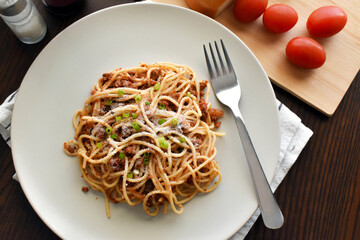 Spaghetti Bolognese with minced beef, onion, chopped tomato, garlic, olive oil, stock cube, tomato puree and Italian herb. Traditional Italian food on a plate. Flat lay top view photo.