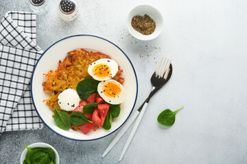 Breakfast. Potatoes latkes with sour cream, spinach salad, tomatoes and boiled eggs on light background. Delicious food for breakfast. Top view.