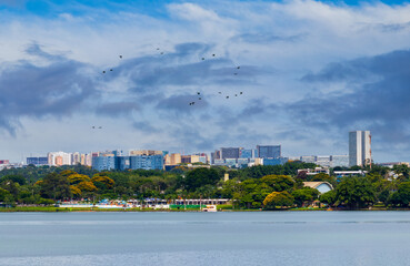 Fototapeta premium Brasilia seen from Lake Paranoá with birds flying under the blue sky.