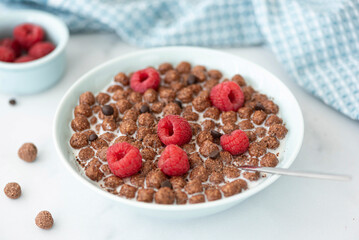 chocolate flakes balls with milk and raspberries in a blue bowl