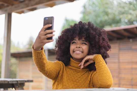 Young afro woman taking a selfie to share on her social networks. With the concept of photographing images to share with friends through her mobile device and digital communities.