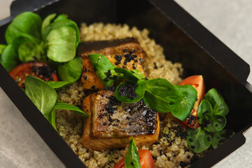 Salmon baked with quinoa and tomatoes. Healthy food, restaurant dish delivery. Top view. Free space for your text. Gray background.