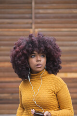 Young afro woman listening to music on her mobile device. Concept of young man enjoying music...