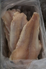 Frozen white fish fillet on the counter in the store. Healthy diet food. Close-up. Vertical.