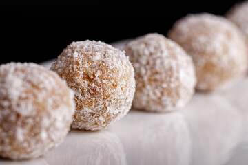 Beautiful sweets with coconut on a white plate on a black background