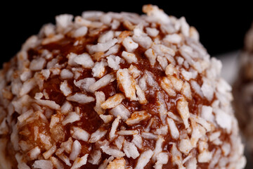 Beautiful sweets with coconut on a white plate on a black background