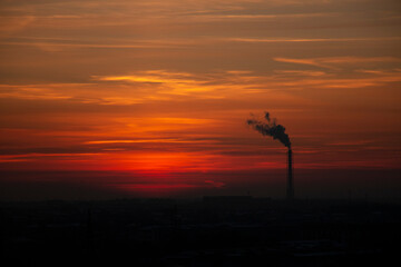 Red-orange sky. Pipe from the factory with smoke. Silhouette