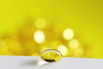 selective focus closeup vitamin supplement soft gel pills in yellow background,copy space