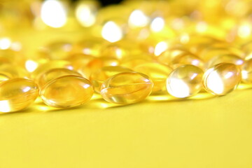 selective focus closeup vitamin supplement soft gel pills in yellow background,copy space