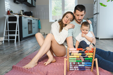Father and mother teach the baby to count on the abacus. The child is learning math.