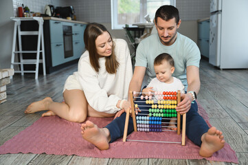 Father and mother teach the baby to count on the abacus. The child is learning math.