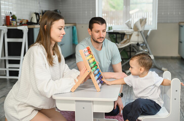 Father and mother teach the baby to count on the abacus. The child is learning math.