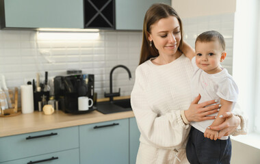 Happy mom and cheerful baby in the kitchen. Mother's love. Motherhood. The child is restless.