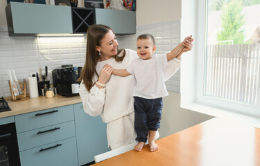 Happy mom and cheerful baby in the kitchen. Mother's love. Motherhood. The child is restless.