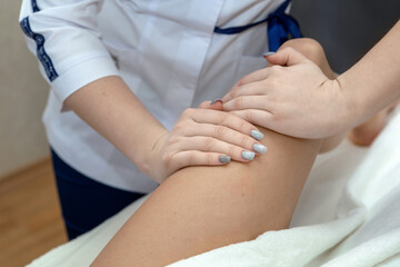 Anti-cellulite massage in the cosmetologist's office.A specialist in a white coat gives a hip...