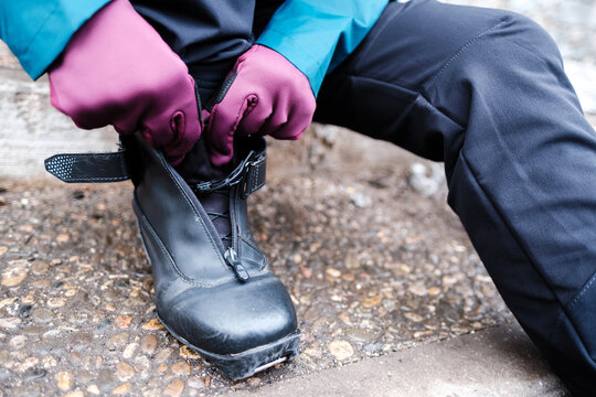 Crop Person Putting On Boots On Street