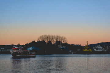 Beautiful sunrise over the lake with red boat and forest silhouette in the back, Valdivia, Chile