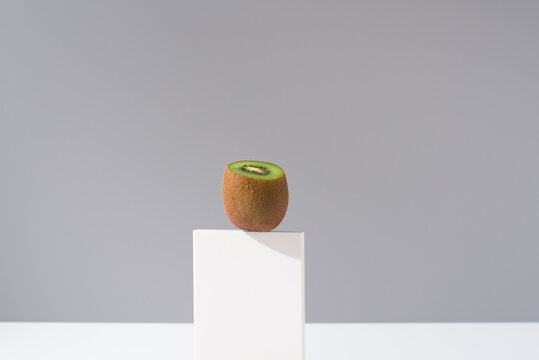 Ripe healthy kiwi placed on white stand in sunlight